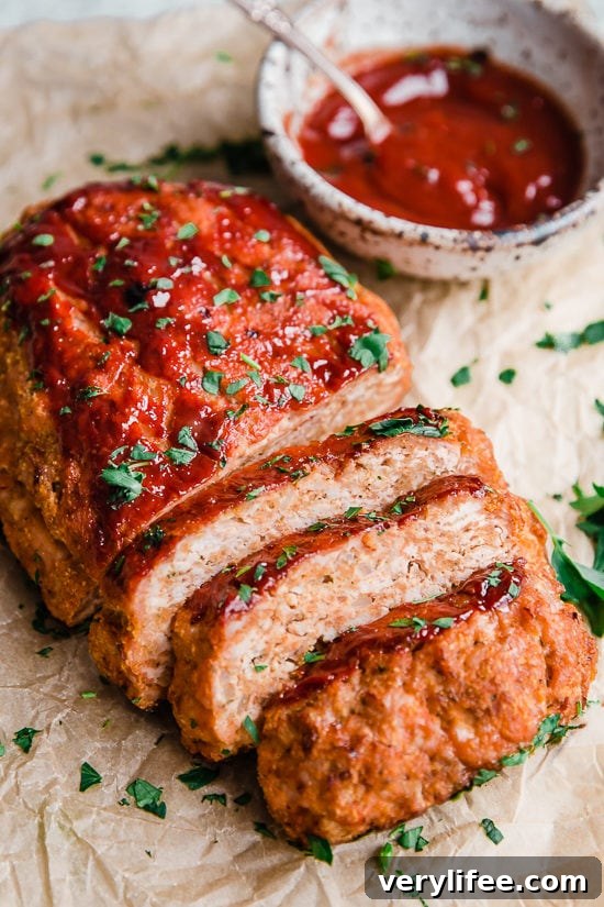 Turkey meatloaf cut into slices next to a bowl of ketchup glaze.