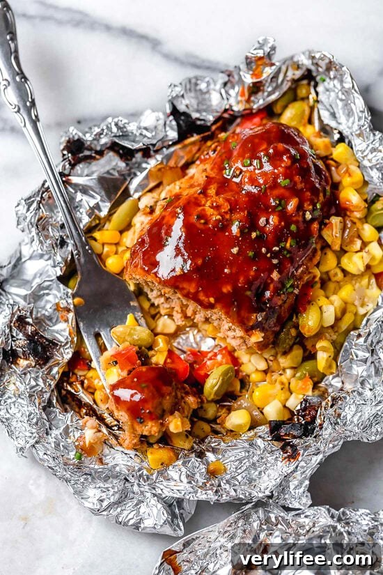 Campfire meatloaf cooked in foil packets with BBQ sauce and succotash.