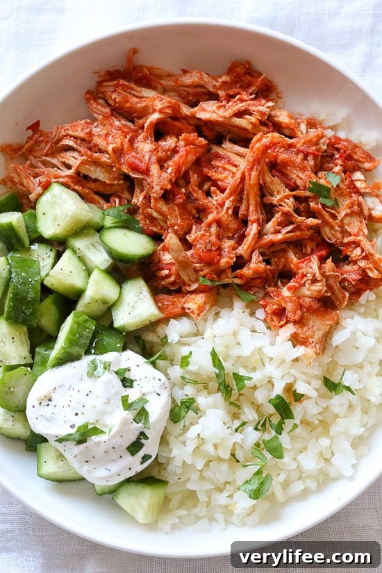 23 Crock Pot Chicken Recipes for Quick Weeknight Dinners 17 Overhead view of a harissa chicken bowl with yogurt sauce, cucumber, and rice.