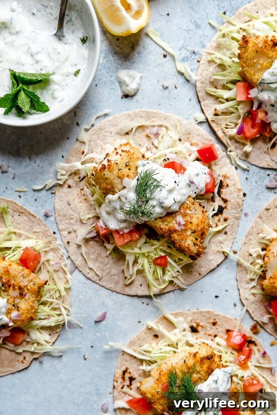 Tzatziki Fish Tacos have a Greek twist! Crisp breaded fish fillets served on tortillas topped with tzatziki sauce made with Greek yogurt, cucumbers and fresh herbs.