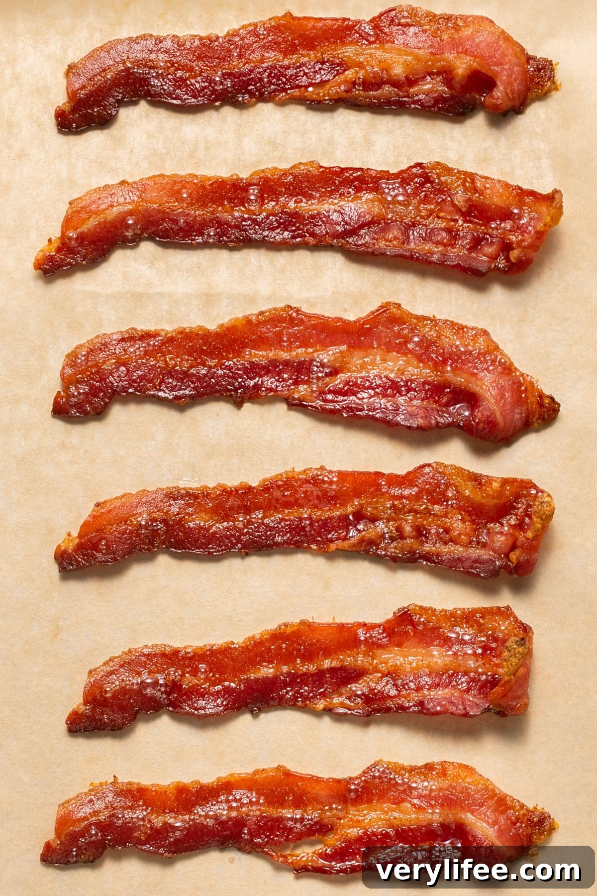 Whether you're a fan of tender, crisp, or extra crispy bacon, this simple method of cooking bacon in the oven is easy. No stovetop mess! Bacon on parchment paper.