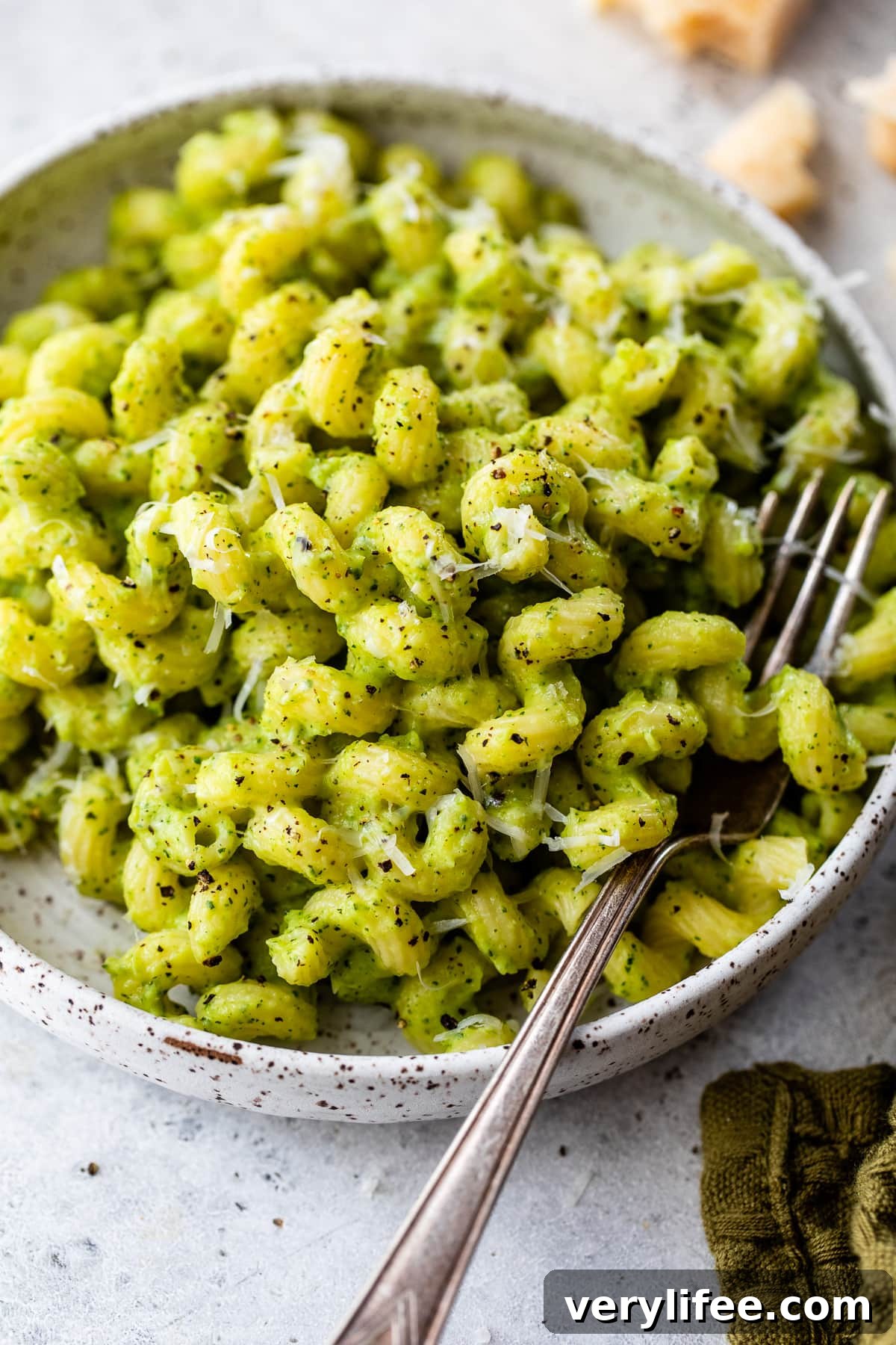 This easy zucchini pasta recipe is made with roasted zucchini, onions, garlic, and Parmesan cheese, blended into a creamy homemade sauce. Close up of pasta with zucchini sauce in a bowl with a fork.