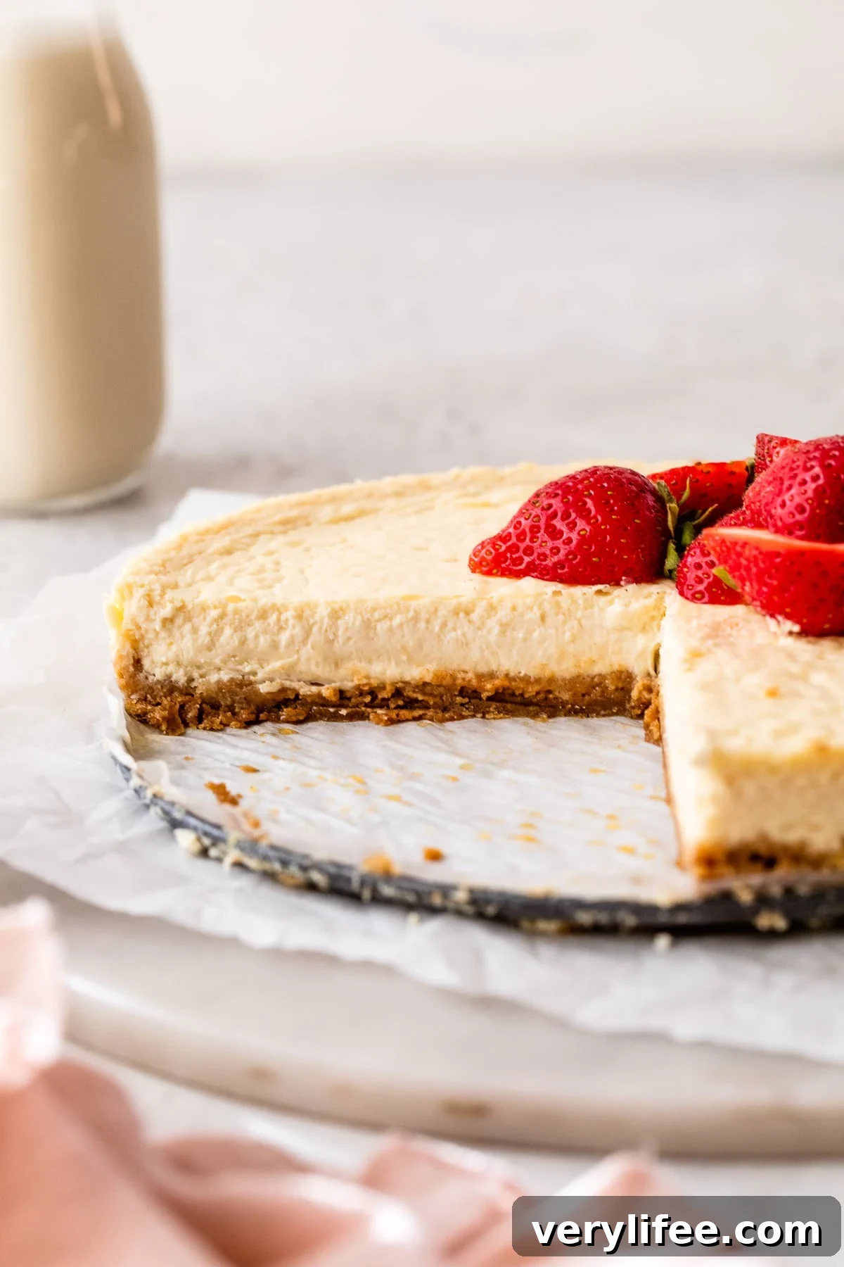 Cottage cheese cheesecake topped with fresh strawberries with a large slice missing.