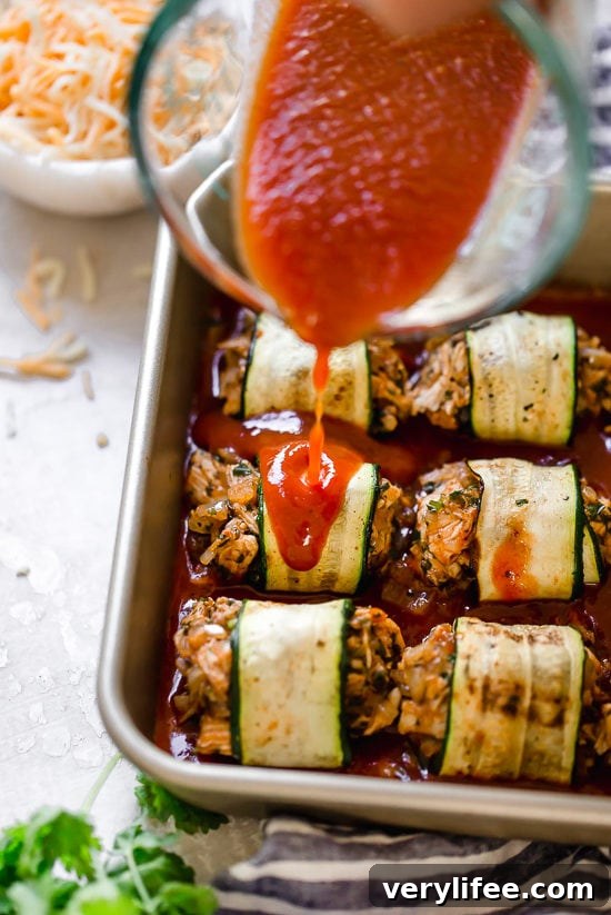 Zucchini enchilada roll ups filled with seasoned chicken and covered in sauce and cheese.