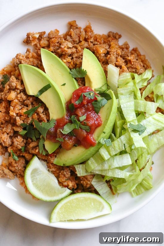 Skillet taco cauliflower rice with ground turkey, lettuce, avocado, and salsa.