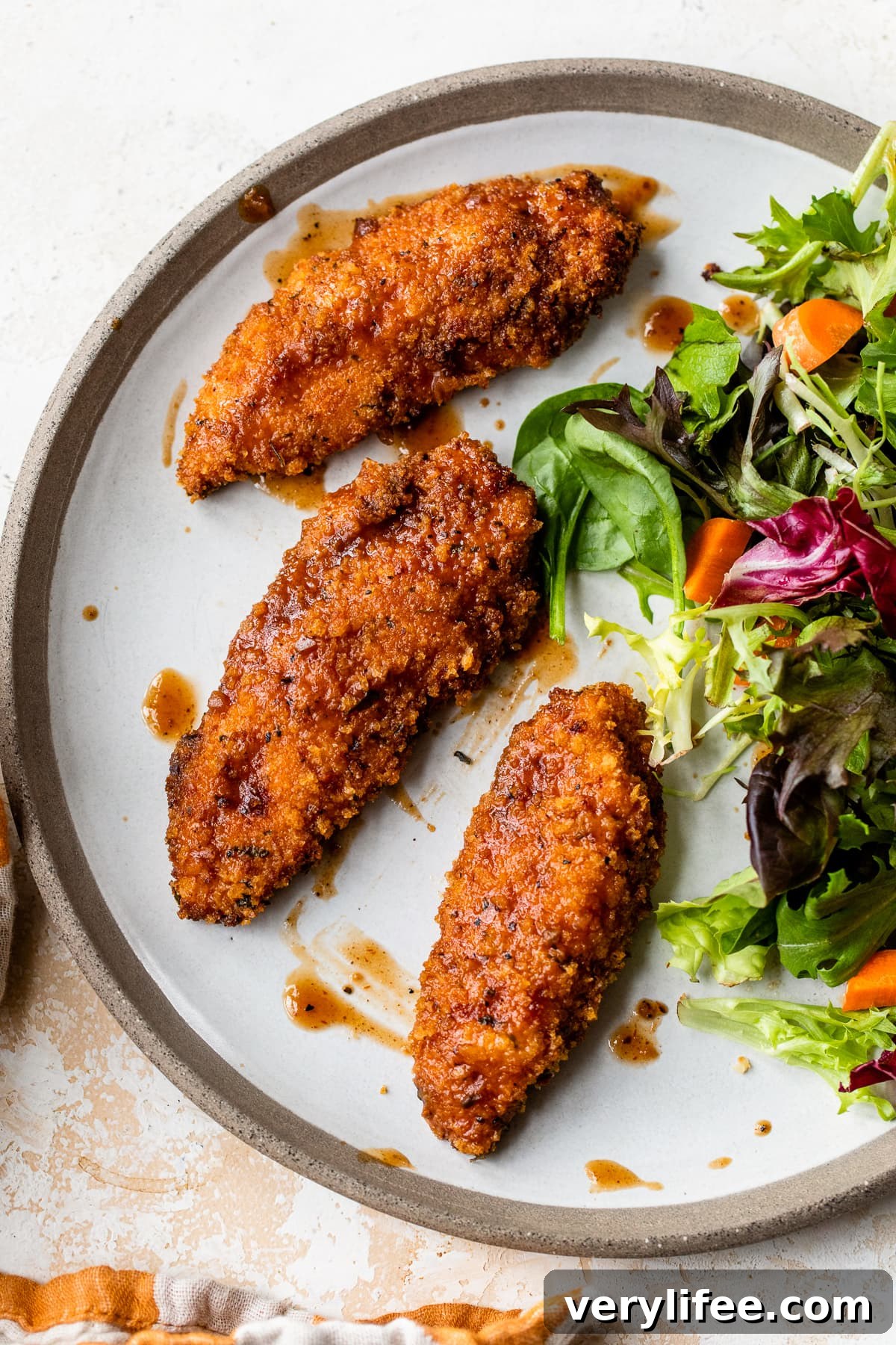 Crispy chicken tenders with salad Crispy chicken tenders with a fresh mixed greens salad on a plate.