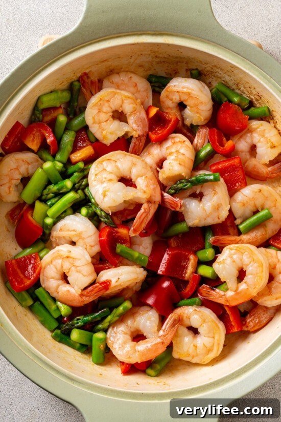 Shrimp, asparagus, and red bell peppers in a frying pan