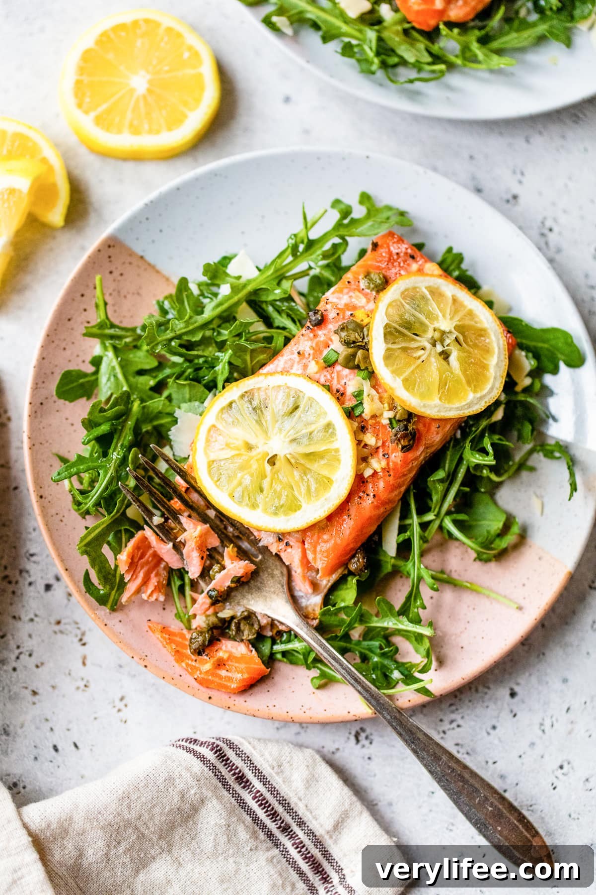 Baked Steelhead Trout with lemon and arugula on a plate