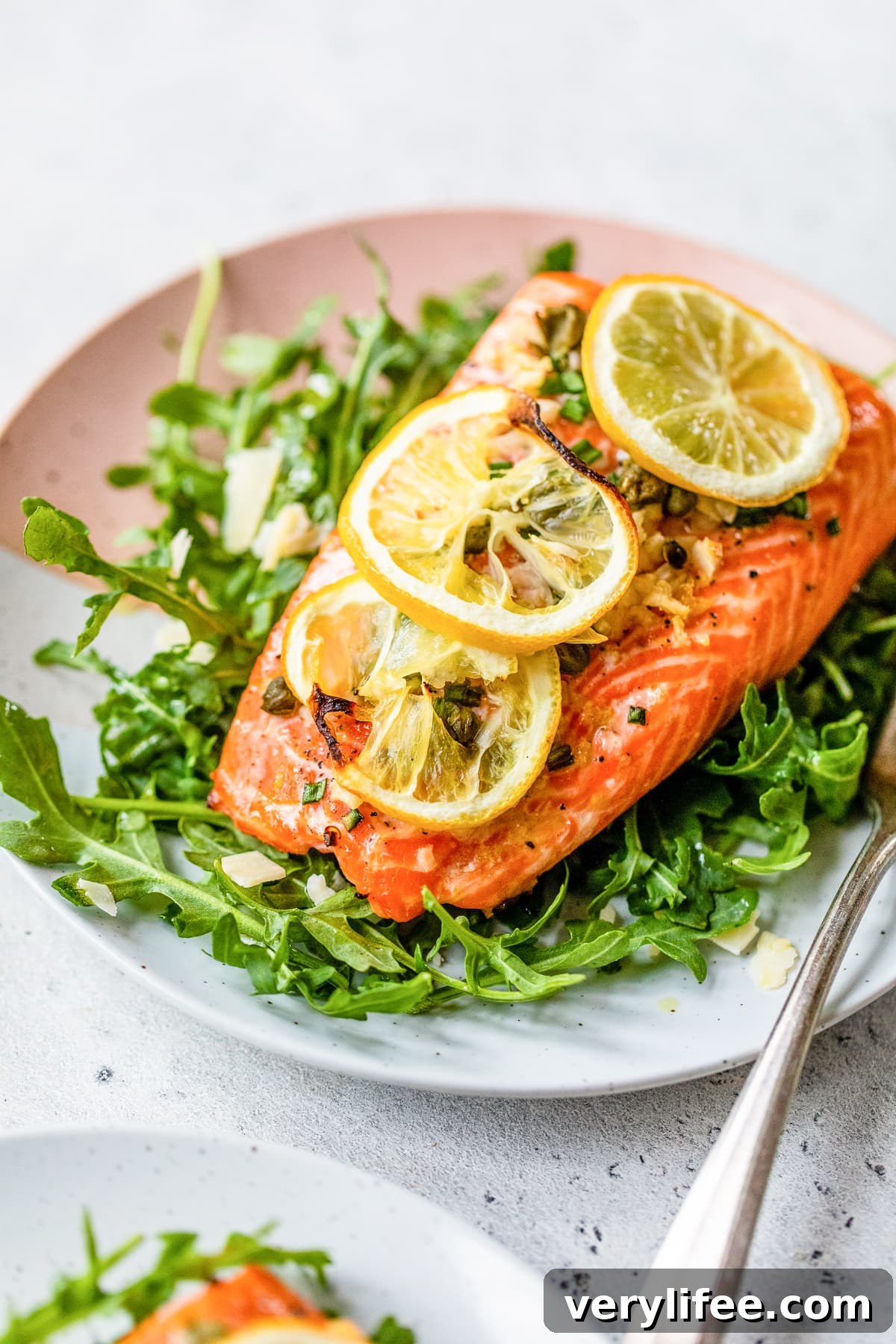 Baked Steelhead Trout with lemon and arugula on a plate