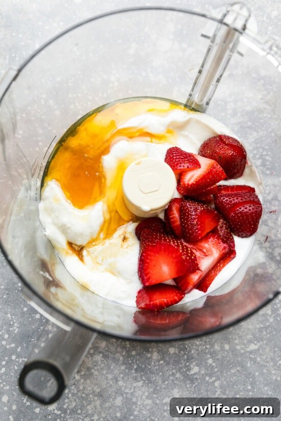 food processor with yogurt, honey and strawberries