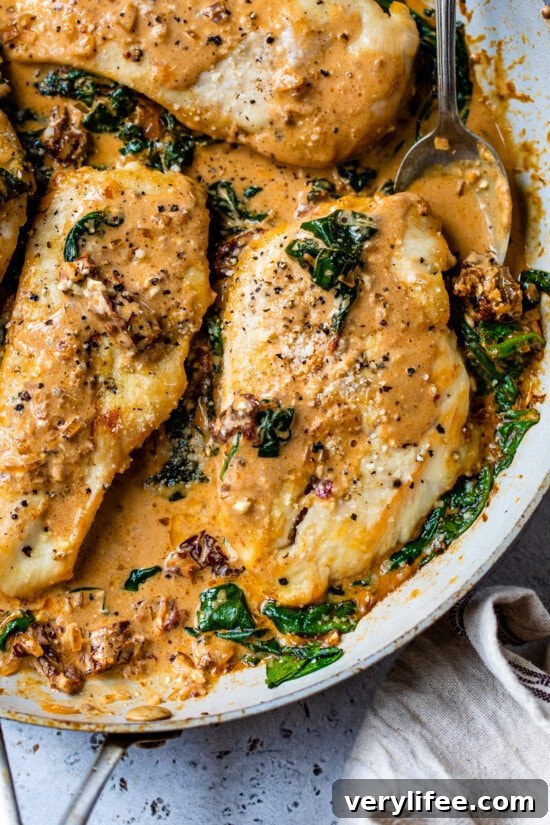 Close up of Marry Me Chicken with creamy tomato sauce and spinach in a skillet.