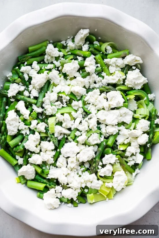 Add veggies and feta to a quiche dish.