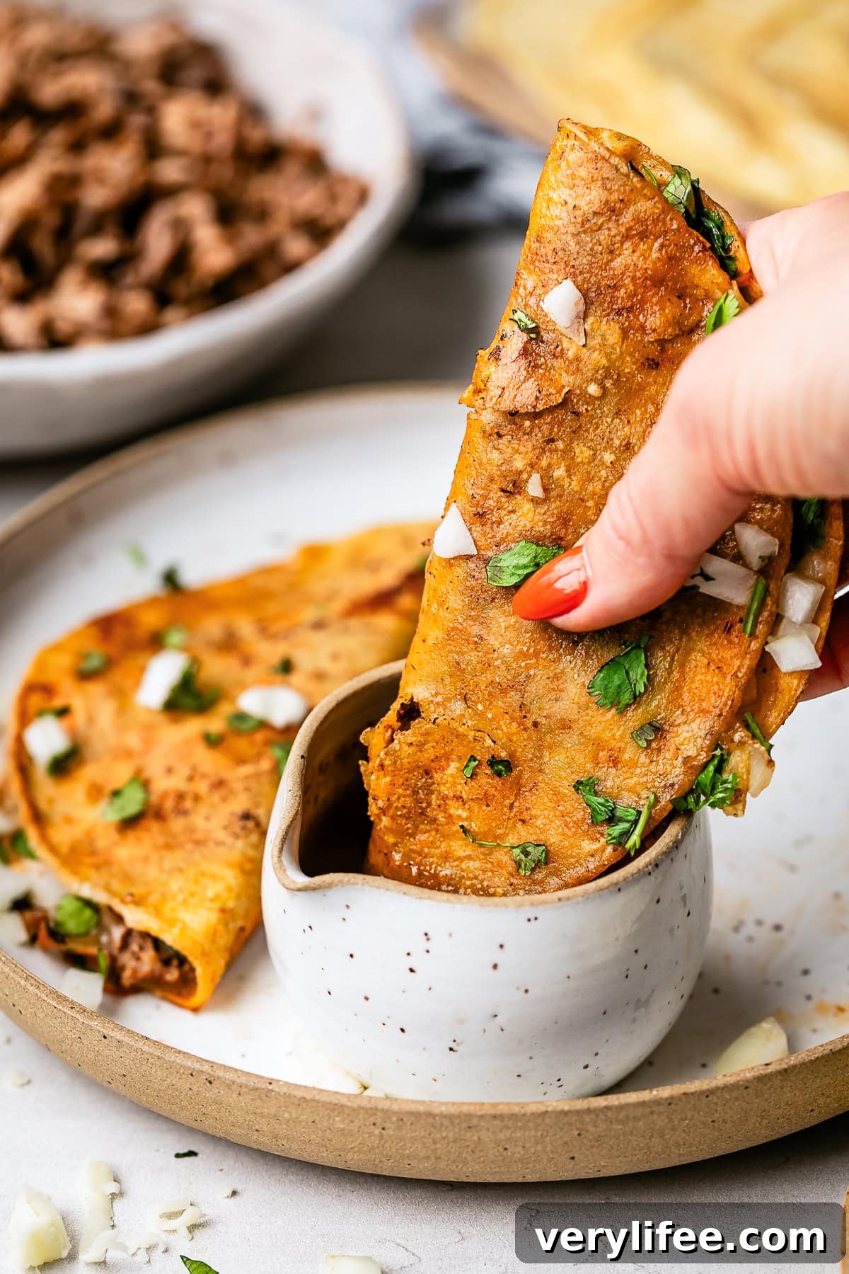 Slow Cooker Birria Tacos Recipe with Dipping Broth 11 Birria Tacos dipped in consommé