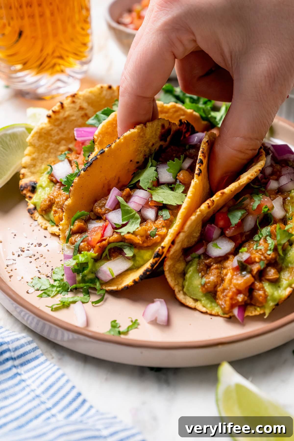 Vegan Lentil Tacos with Spiced Tomato Salsa 11 Hand lifting lentil taco from plate