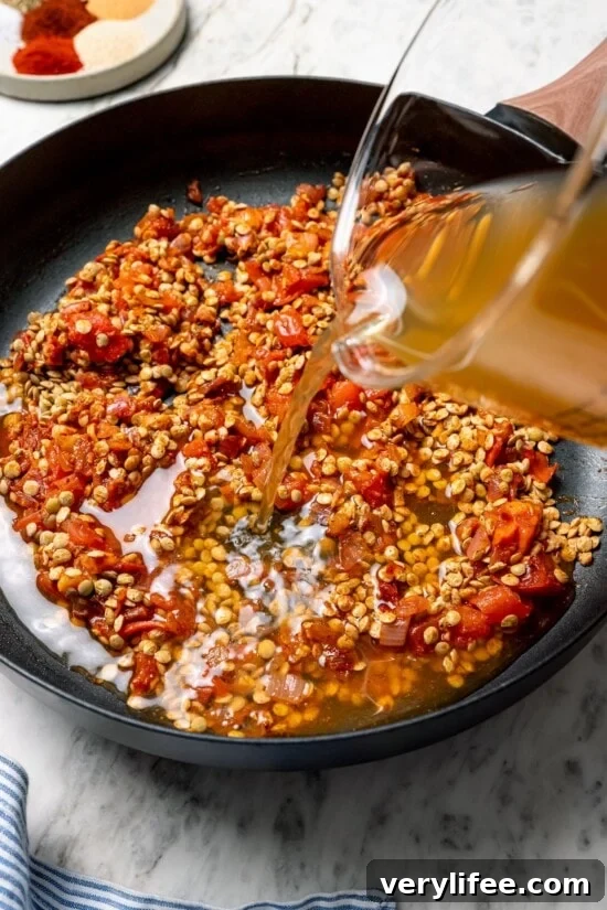 Vegan Lentil Tacos with Spiced Tomato Salsa 8 Pouring broth into pan with lentils and tomatoes