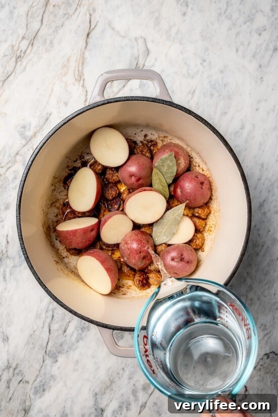 Pouring water into Dutch oven with bay leaves and potatoes