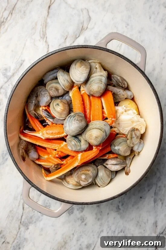 Overhead view of clams, shrimp, and crab legs added to Dutch oven