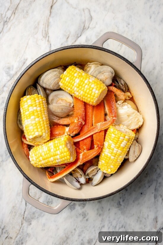 Overhead view of corn added to pot of seafood