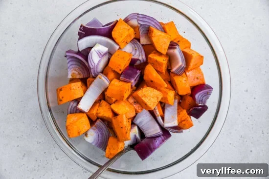 Potatoes, red onion in a bowl with seasoning.