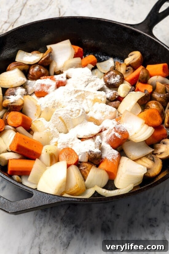 Flour sprinkled over vegetables in skillet.