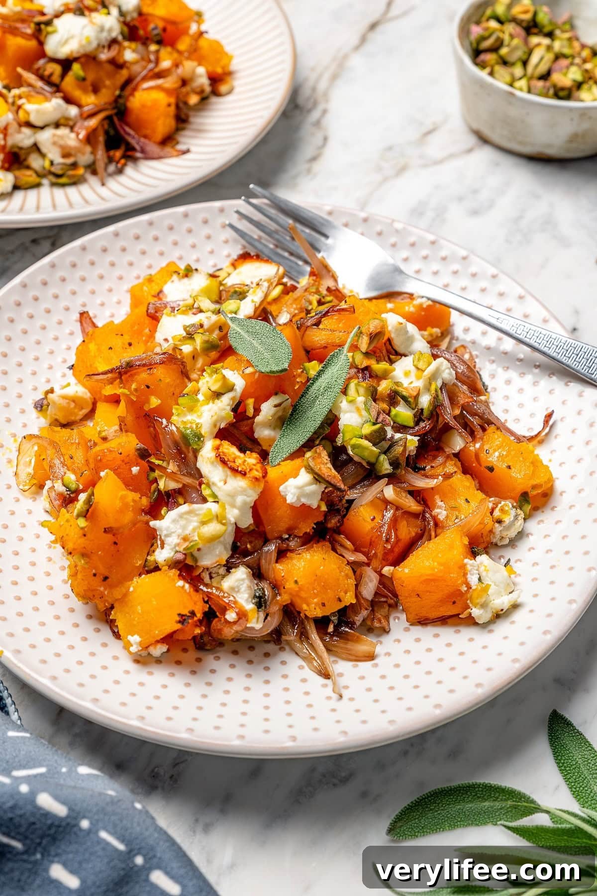 Butternut squash bake on plate with goat cheese, pistachios, and sage.