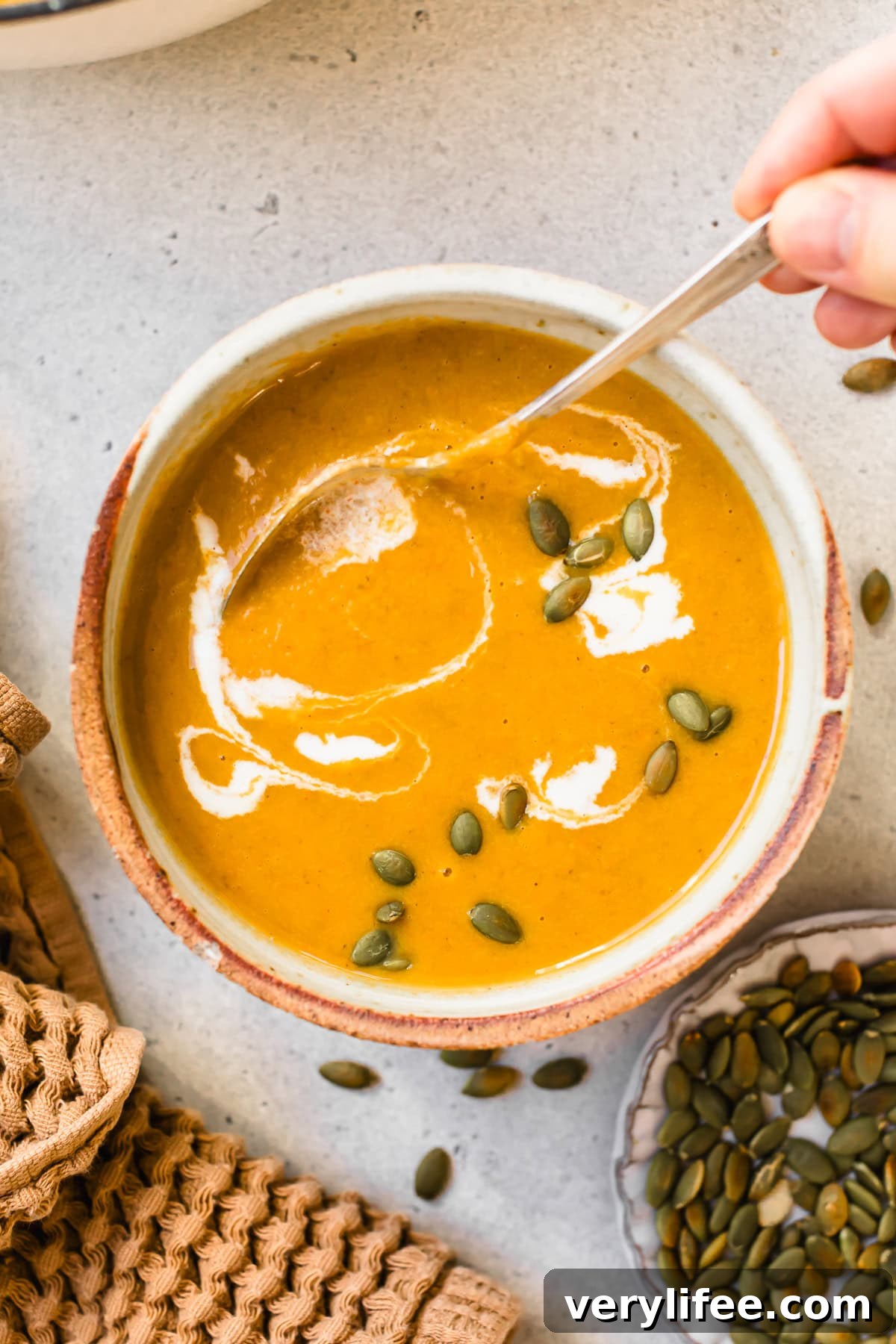 Creamy Pumpkin Ginger Coconut Soup — Dairy-Free 9 Pumpkin Ginger Coconut Soup topped with a swirl of coconut milk and pepitas.