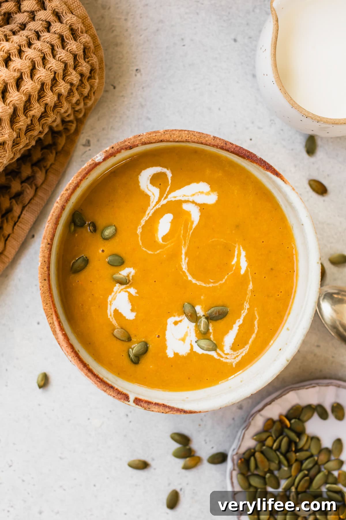 Creamy Pumpkin Ginger Coconut Soup — Dairy-Free 8 Pumpkin Ginger Coconut Soup topped with a swirl of coconut milk and pepitas.
