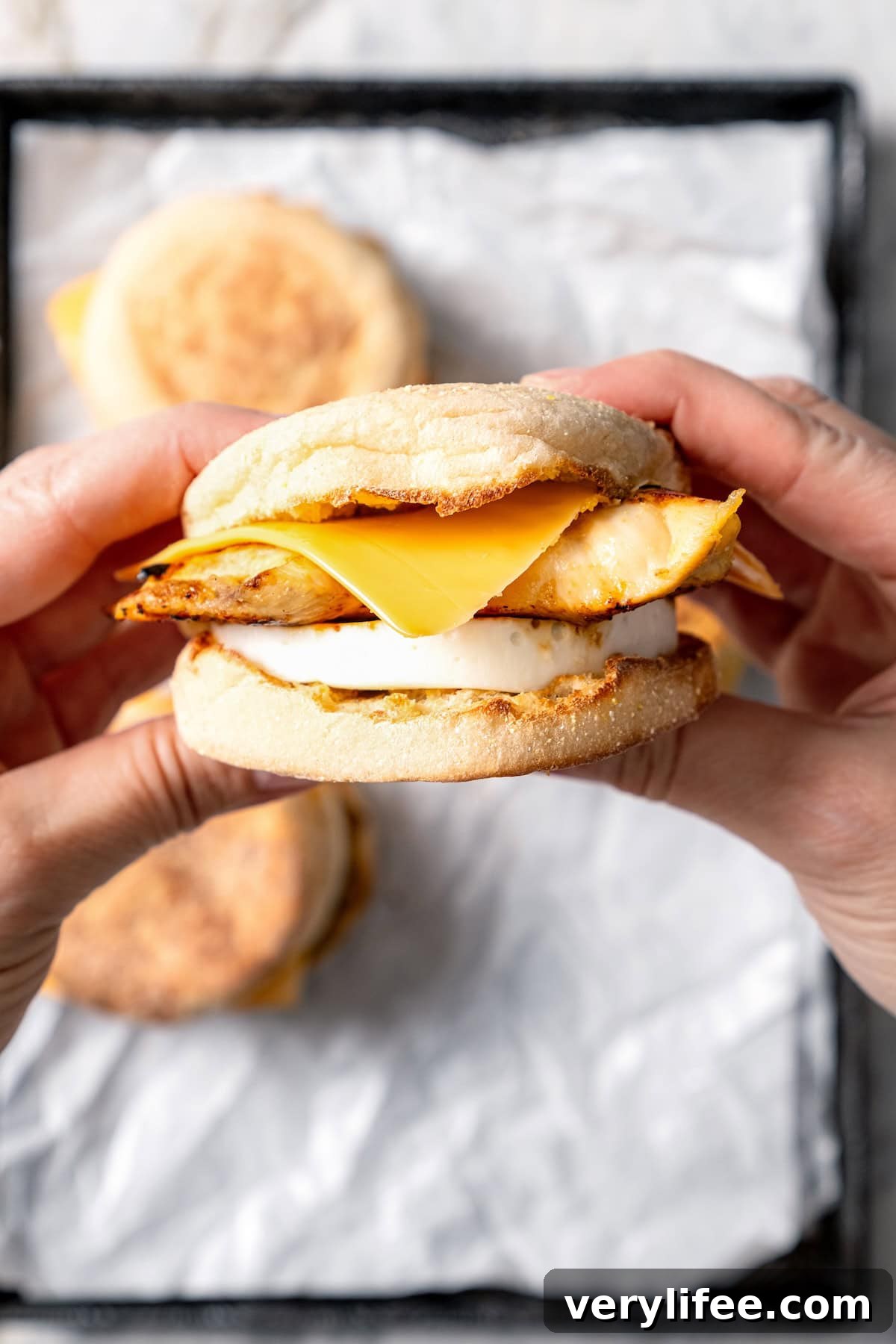 Two hands holding egg white grill breakfast sandwich.