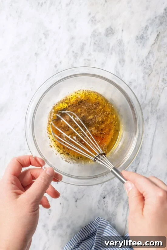 Classic Greek Salad Dressing Recipe with Olive Oil and Herbs 6 Whisking Greek salad dressing in small glass bowl.