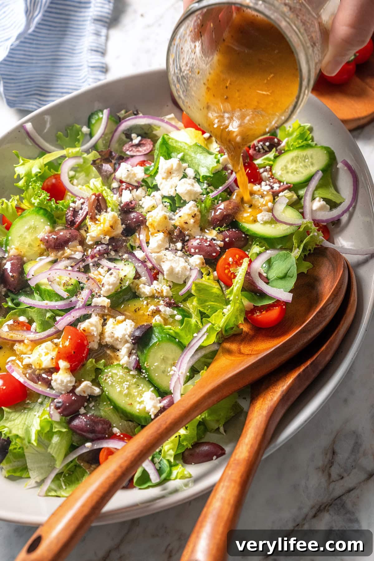 Classic Greek Salad Dressing Recipe with Olive Oil and Herbs 7 Pouring Greek salad dressing over bowl of salad.