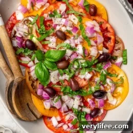 Protein-Packed Vegan Quinoa Bowl with Roasted Veggies and Tahini 9 Overhead view of heirloom tomato salad on platter with serving spoons