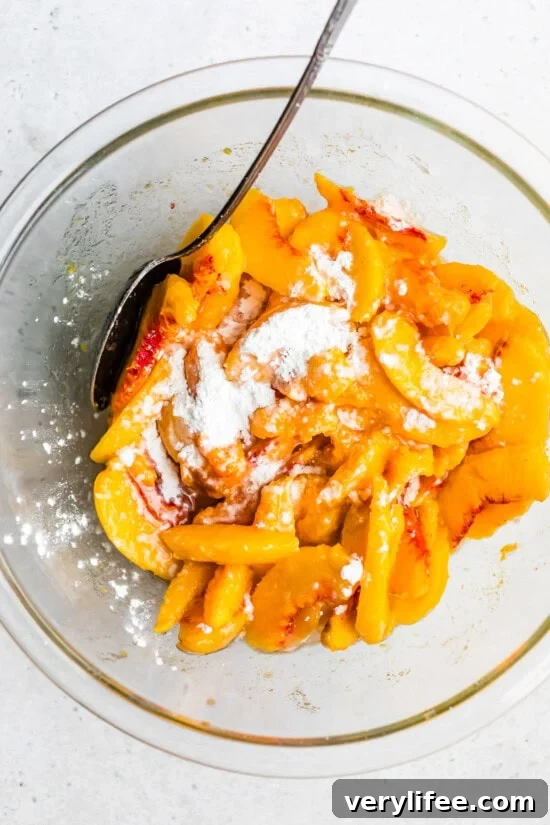 Classic Peach Crisp Recipe with Oat Streusel 5 peaches and cornstarch in a bowl