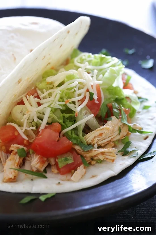 Instant Pot salsa chicken served in a flour tortilla with taco toppings.