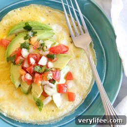 Open-faced omelet topped with avocado slices and pico de gallo