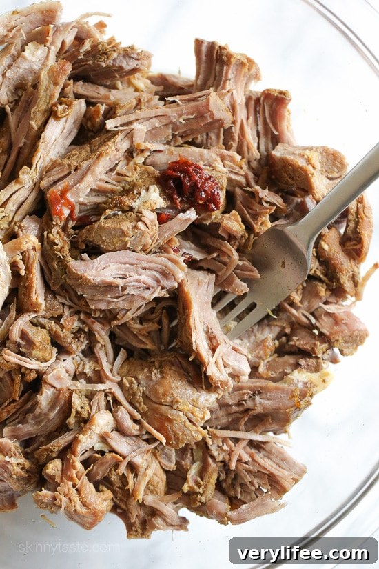 Instant Pot Carnitas: Authentic Mexican Pulled Pork 3 Instant Pot pork carnitas in a glass bowl with a fork, after shredding.