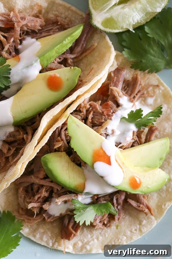 Instant Pot Carnitas: Authentic Mexican Pulled Pork 8 Overhead view of Instant Pot carnitas tacos on a plate topped with avocado slices, cilantro, and cheese.