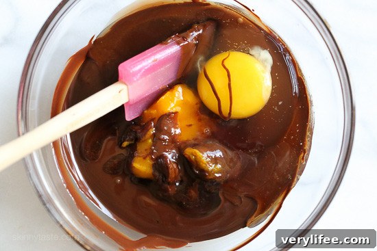 Eggs and pumpkin being stirred into melted chocolate