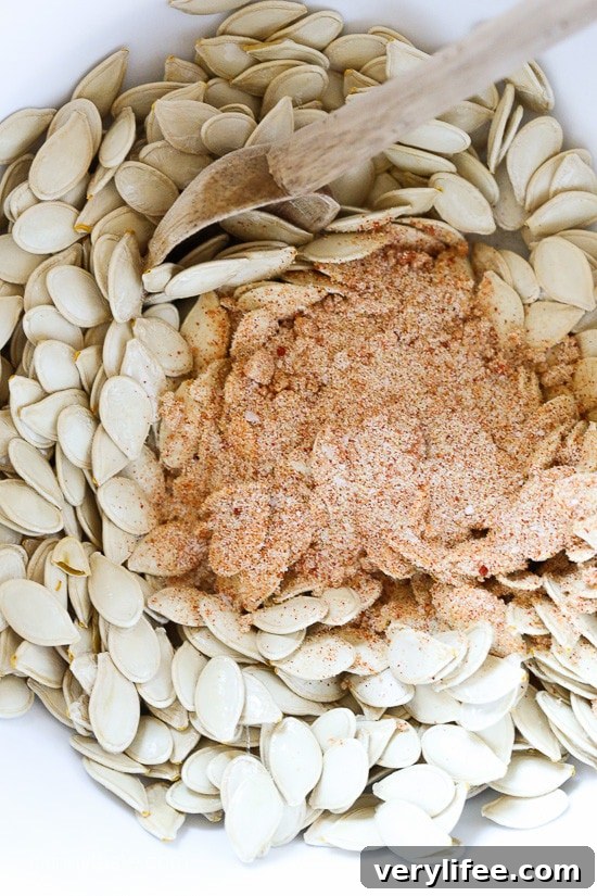 These Spicy Pumpkin Seeds are a fun twist on roasted pumpkin seeds. They make a tasty, filling snack on their own and a great salad topper. A seasoning mixture on top of pumpkin seeds in a bowl