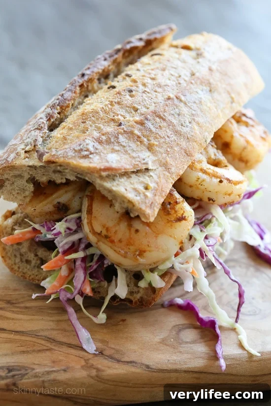A shrimp po' boy sandwich on a wooden cutting board.