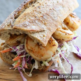 A shrimp po' boy sandwich on a wooden cutting board.