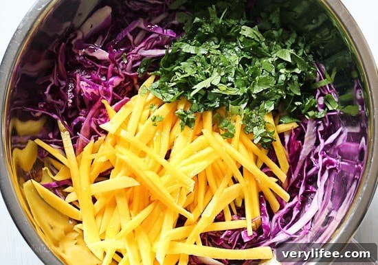 Blackened Fish Tacos with Mango Cabbage Slaw Recipe 2 A mixing bowl with shredded red cabbage, julienned mango, and chopped cilantro