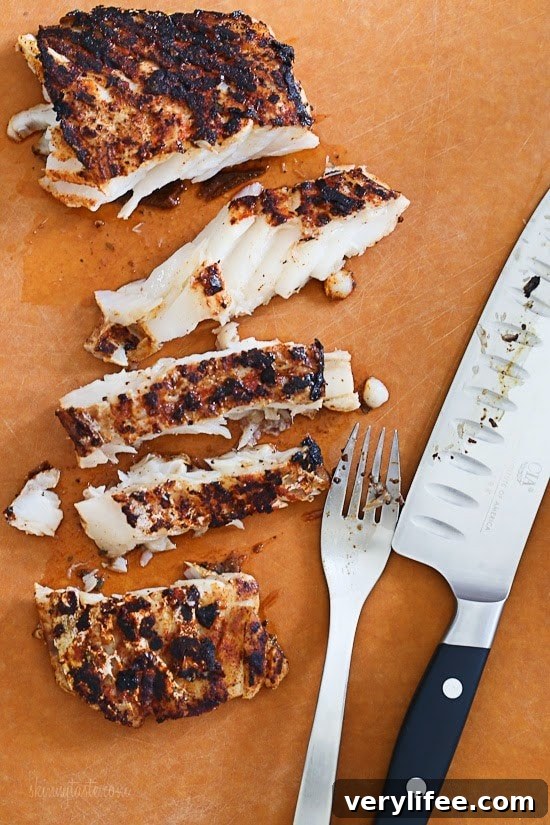 Blackened Fish Tacos with Mango Cabbage Slaw Recipe 5 A cutting board with blackened grilled white fish cut into a few slices