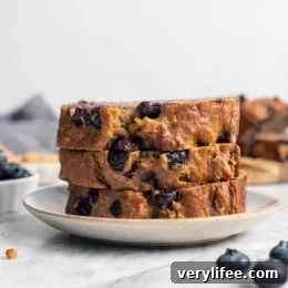 Moist Blueberry Banana Bread Recipe 5 Stack of 3 blueberry banana bread slices on plate.