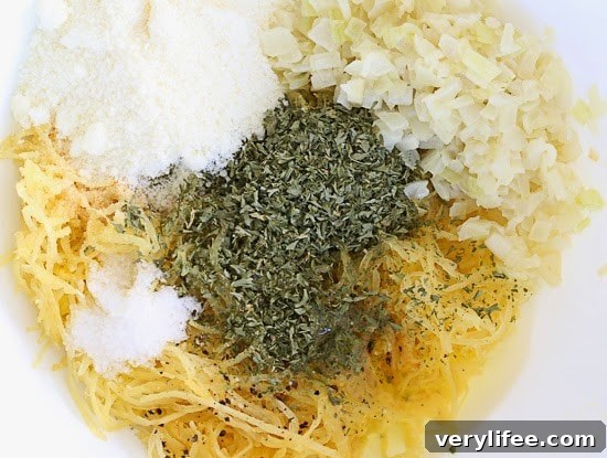 Spaghetti Squash Nests with Baked Eggs Recipe 5 A mixing bowl with cooked spaghetti squash, diced onion, grated Pecorino Romano cheese, and dried herbs