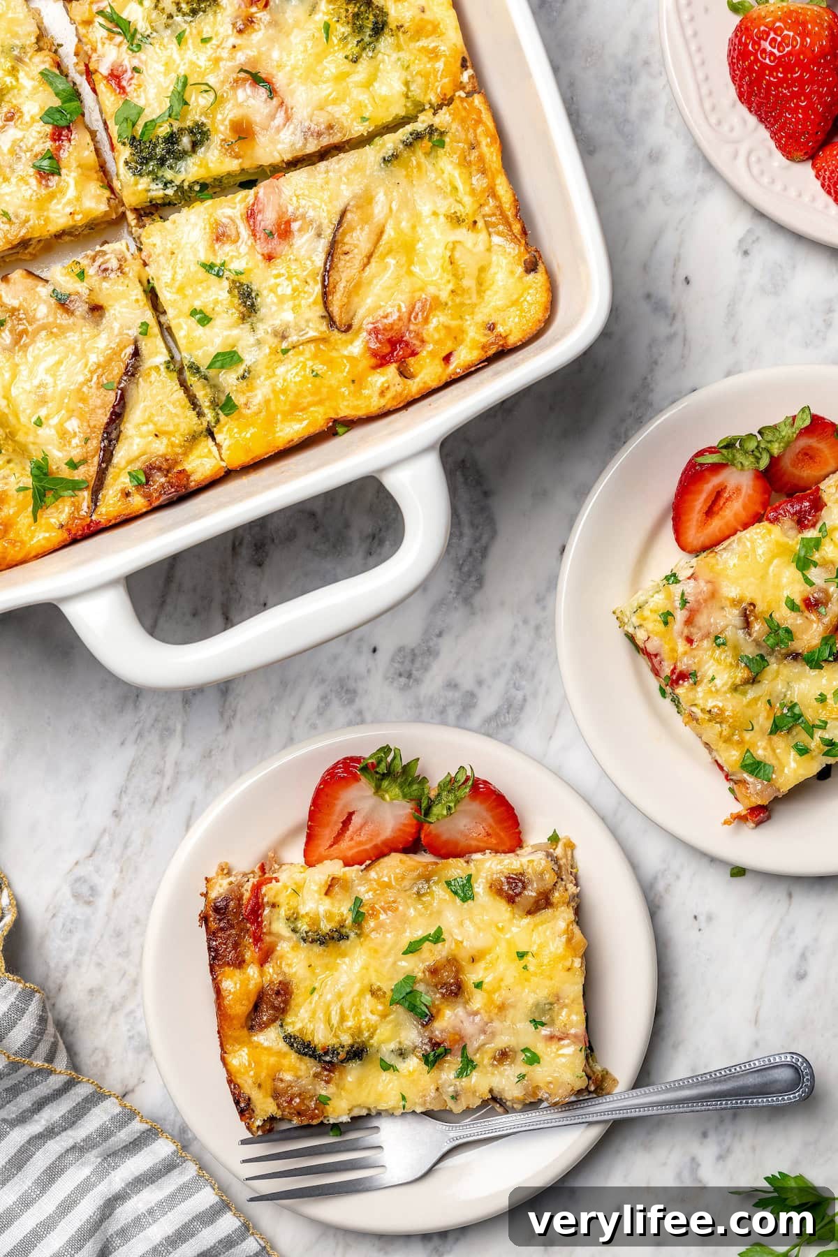 Two plates of breakfast casserole set next to baking dish.