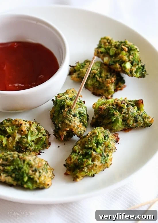 A plate of broccoli tots with a bowl of ketchup dipping sauce