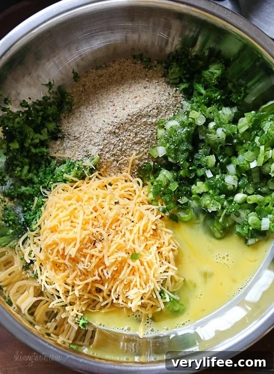 A mixing bowl with chopped broccoli, breadcrumbs, sliced scallions, grated cheese and egg