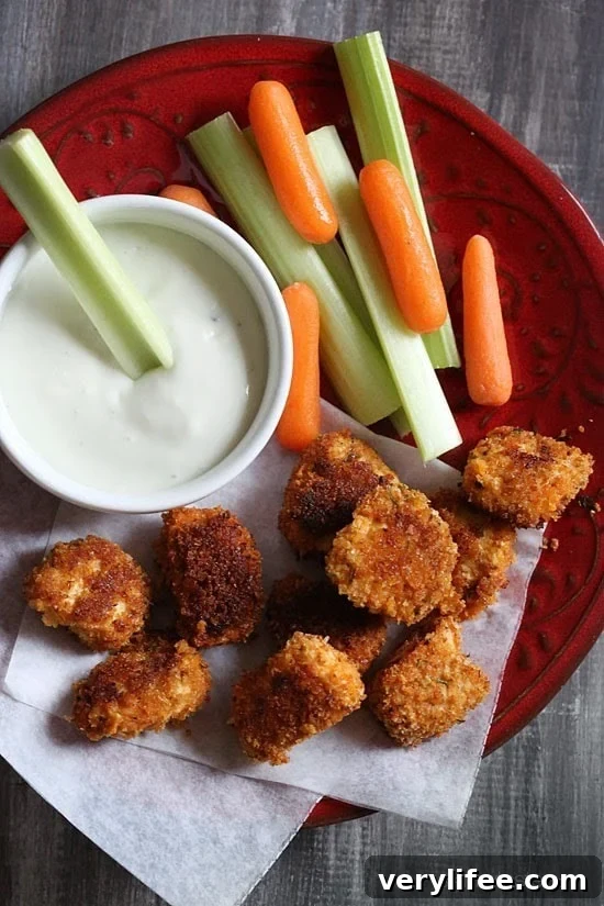 Crispy Oven-Baked Buffalo Chicken Nuggets 2 A plate of crispy breaded buffalo chicken nuggets with celery and carrot sticks and creamy dipping sauce.