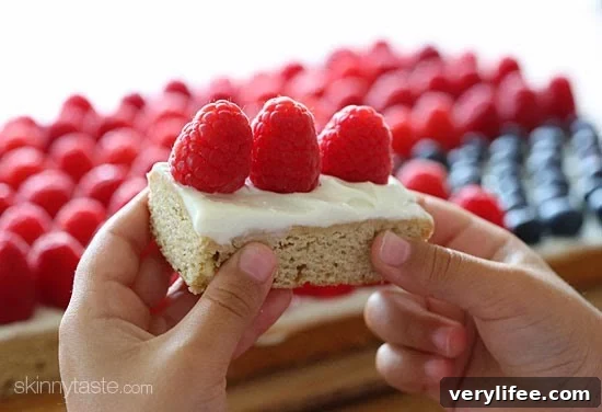 Red, White and Blue fruit "pizza" is more like a cookie bar, topped with cream cheese frosting and fruit – The perfect 4th of July dessert!