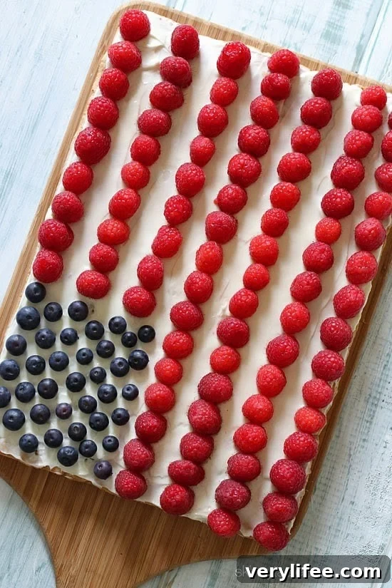 Red, White and Blue fruit "pizza" is more like a cookie bar, topped with cream cheese frosting and fruit – The perfect 4th of July dessert!
